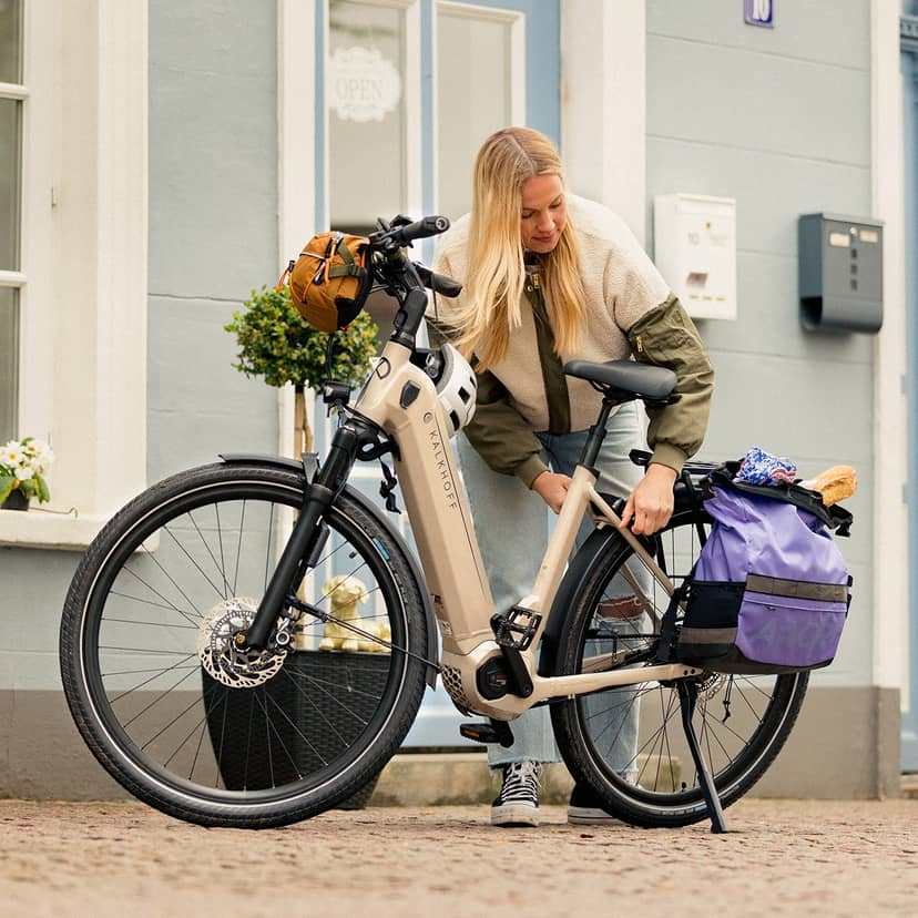 Wood table with porcelain mug, leather journal, brass pen, leather key ring, and a houseplant.