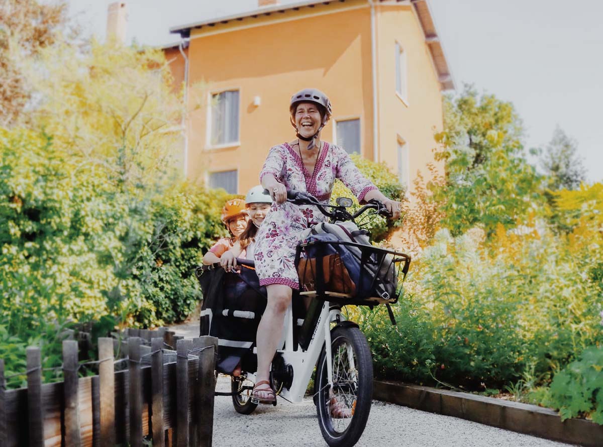 Une maman conduisant un vélo cargo Add-bike, avec ses enfants